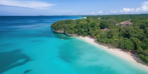 A beautiful blue ocean with a sandy beach and trees in the background. The sky is clear and the water is calm