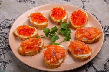 Canapes with red caviar and salmon on a plate decorated with cilantro