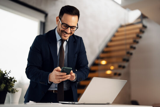 Image of handsome well dressed businessman working at his bright office 