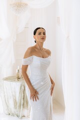 Stylish portrait of a cute beautiful bride in a white dress with decor. Wedding dresses and bridal gowns as trends of the year