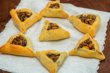 Sweet pastries triangular gomentashi ears of Haman for Purim on a wooden board