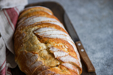 Close-up of a Freshly sliced  homemade  white sourdough loaf on a wooden chopping board with a tea towel