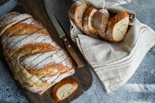 Close-up of Freshly sliced  sourdough bread in a bread basket next to a sliced loaf of brad on a chopping board