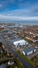 Fototapeta premium Aerial view of a coastal industrial area showcasing warehouses, residential neighborhoods, and harbor activities in a bustling seaside town during daytime