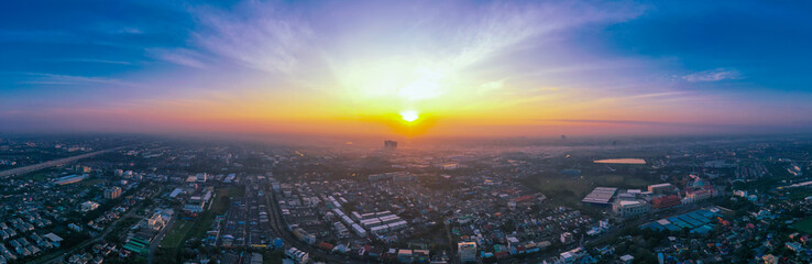 view of sunset city skyline, transportation with cars on Expressway, Road, Roundabout, multilevel junction highway-Top view. Important infrastructure, cloudscape, cityscape, building, crane.
