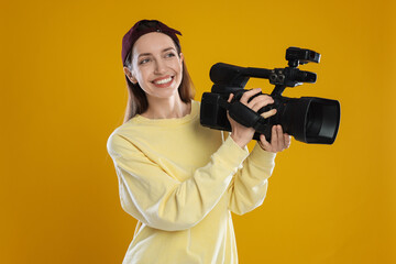 Happy woman with professional video camera on orange background