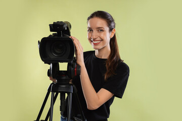 Happy woman with professional video camera on pale olive background