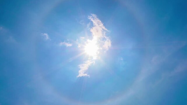 Magnificent sun halo surrounded by white clouds against a bright blue sky during midday