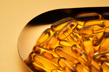 Yellow capsules with Omega-3 fish oil on a golden tray.