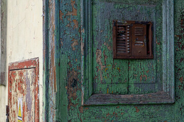 an old rusty intercom hung on the wooden entrance door to an old ruined tenement house