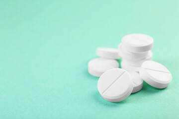 Pile of antibiotic pills on turquoise background, closeup. Space for text