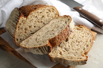Cut loaf of fresh bread and knife on table, closeup