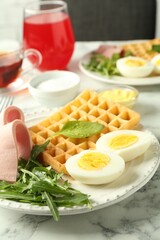 Tasty brunch. Boiled egg, Belgian waffle, arugula and ham on white marble table, closeup