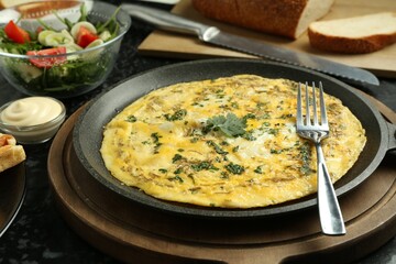 Tasty brunch. Delicious omelette and salad served on black textured table, closeup