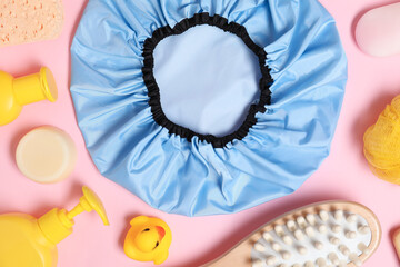 Shower cap and bath accessories on pink background, flat lay © New Africa