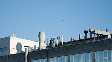 Obraz premium ventilation pipes on the roof of an industrial gray building against a blue sky