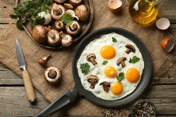 Tasty fried eggs with mushrooms and parsley served on wooden table, flat lay