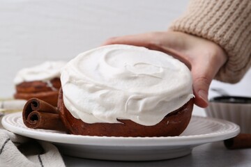 Woman tasty cinnamon roll at table, closeup