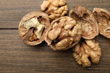 Fresh walnuts with shells on wooden table, flat lay