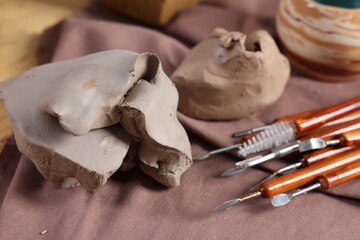 Set of different crafting tools and pieces of clay on table, closeup