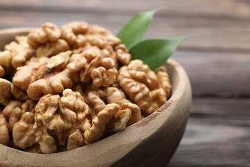 Peeled walnuts in bowl on wooden table, closeup