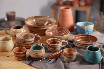Different beautiful pottery and set of clay crafting tools on table indoors