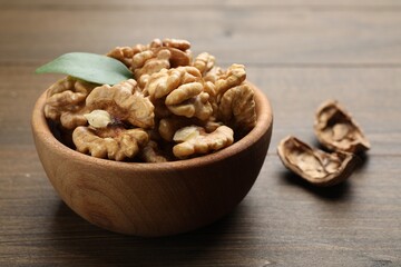 Peeled walnuts in bowl on wooden table, closeup