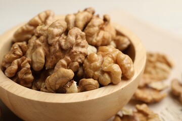 Peeled walnuts in bowl on light table, closeup