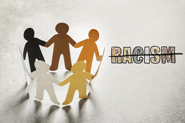 Stop racism. Paper people in different colors holding hands and strikethrough word on light...