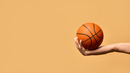 Arm extended outward, gripping basketball firmly, demonstrating stability, technique, and readiness to make powerful play against warm-toned background. Concept of sport equipment, control, strategy.