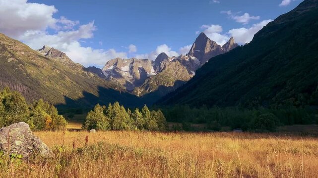 Teberdinsky Nature Reserve. View of Kosygin's glade in the Gonachkhir gorge and the top of Dombai-Ulgen mountain near Lake Tumanly-Kel on a sunny summer day. Panoramic landscape. Resort. 4K