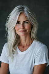 Fototapeta premium Elegant mature woman with silver hair and green eyes posing against a dark gray background