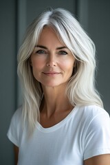 Fototapeta premium Elegant woman with silver hair and gentle smile poses for a portrait against a gray background