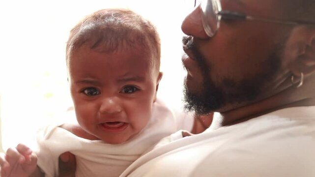 Father, crying baby and comfort, kiss and care, love and bonding in family home together. Dad, sad infant and parent support newborn, holding frustrated young kid and calm child, stress and console