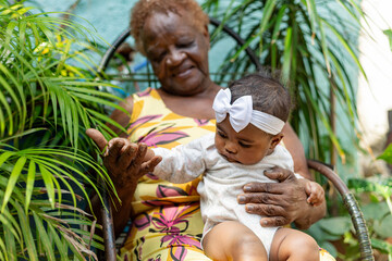 Happy black Great-grandmother with her newborn granddaughter on her lap in a natural environment...