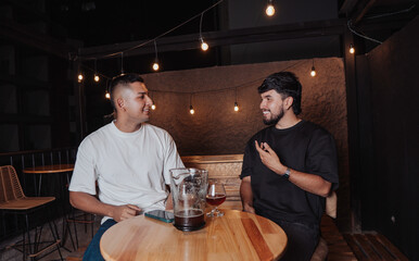 friends talking at a bar table with beer at night