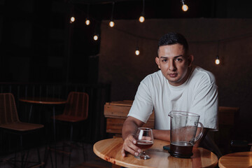 latin man having a glass of beer in a bar at night
