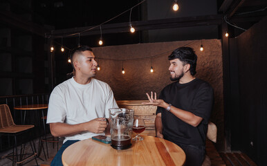 friends talking at a bar table with beer at night