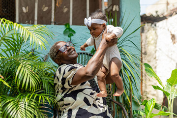 Happy black grandmotherr with her newborn granddaughter on her lap in a natural environment with...