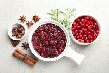 Tasty cranberry sauce in gravy boat, honey, spices and berries on light table, flat lay