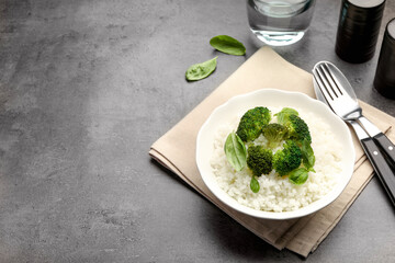 Tasty rice with broccoli served on grey table, space for text