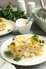 Tasty pasta casserole with cheese and broccoli served on grey table, closeup