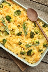 Tasty pasta casserole with cheese, rosemary and broccoli in baking dish on wooden table, top view
