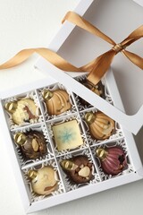 Box with tasty chocolate candies in shape of baubles on white background, top view