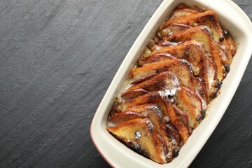 Freshly baked bread pudding in baking dish on grey textured table, top view. Space for text