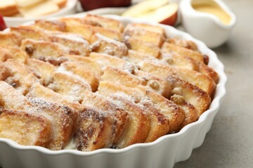 Delicious bread pudding with raisins and powdered sugar on grey table, closeup