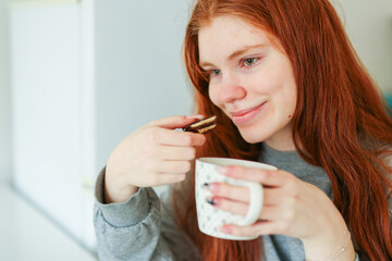 girl with red hair eating chocolate with pistachio filling