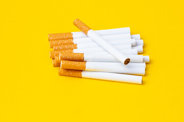 Pile of cigarettes with filter and tobacco separated on the yellow background.