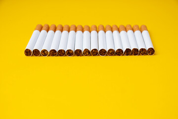 Line of cigarettes which made lung cancer and another diseases with filter and tobbaco separated on the yellow background.
