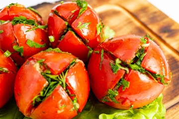 Freshly prepared tomatoes with herbs arranged on a wooden board